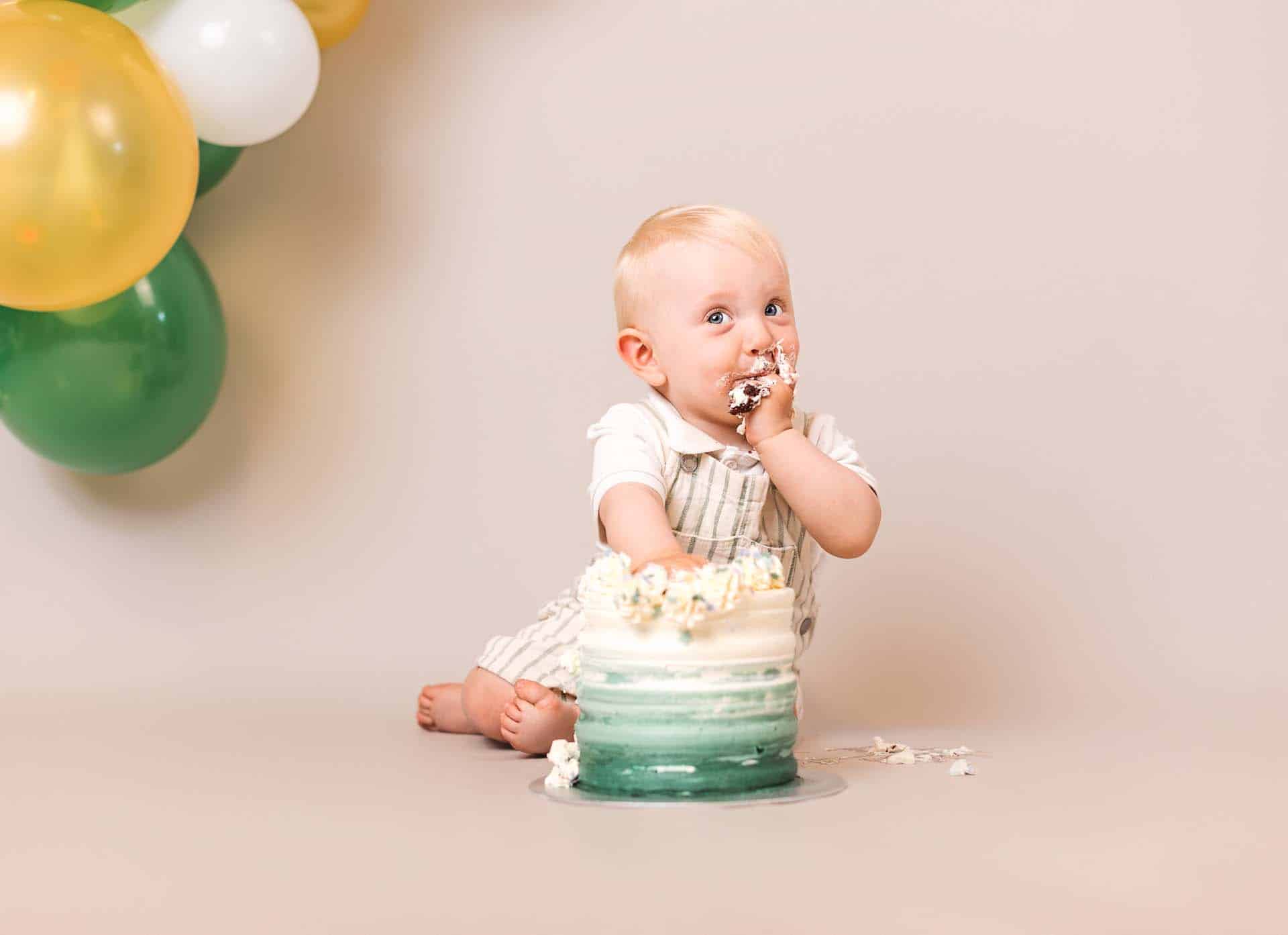Liten gutt får ett-årsfoto med Cake Smash, hvit og grønn kake, barnefoto