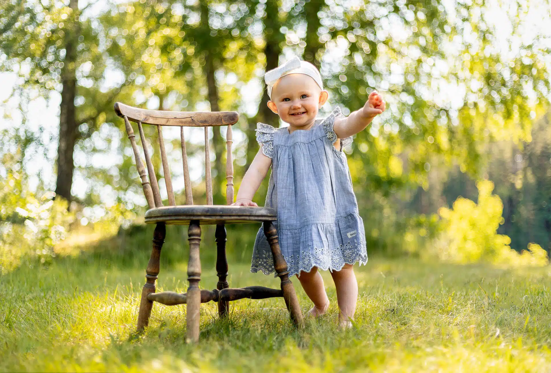 En liten jente som lener seg på en eldre trestol ute i en liten skog, barnefoto