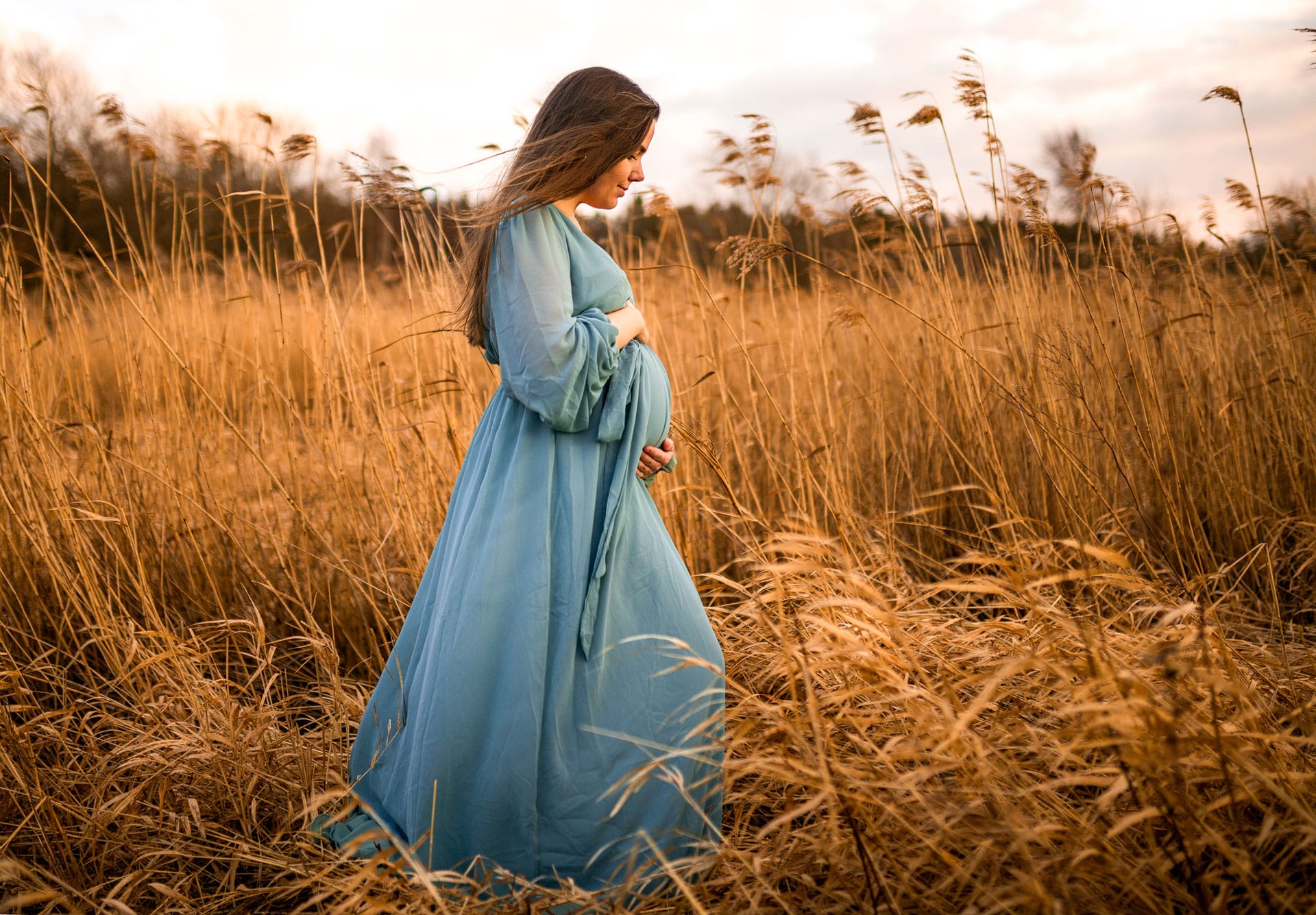 Gravid dame i en høståker, har på seg blå kjole, gravidfoto
